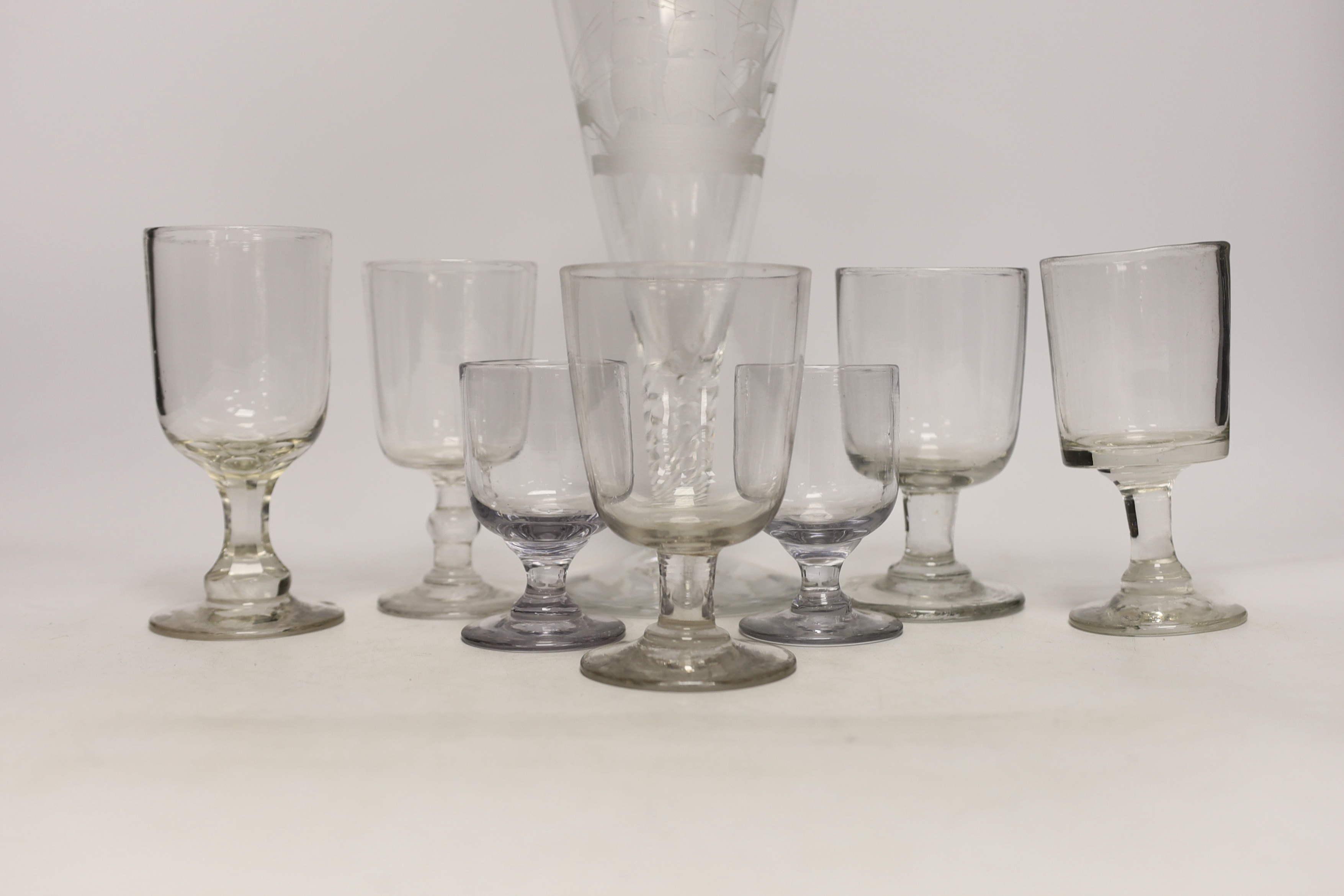 Eight 19th century drinking glasses including a large example with wrythen stem, etched with a naval ship, 27cm high